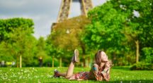 Femme allongée dans l'herbe au pied de la Tour Eiffel