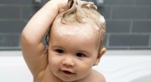 un bébé se lave les cheveux dans son bain