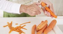 Une personne épluche des carottes vigoureusement dans sa cuisine