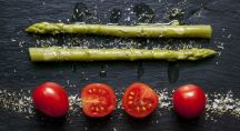 des asperges au dessus de tomates sur une ardoise