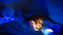 Une petite fille dans son lit avec une veilleuse