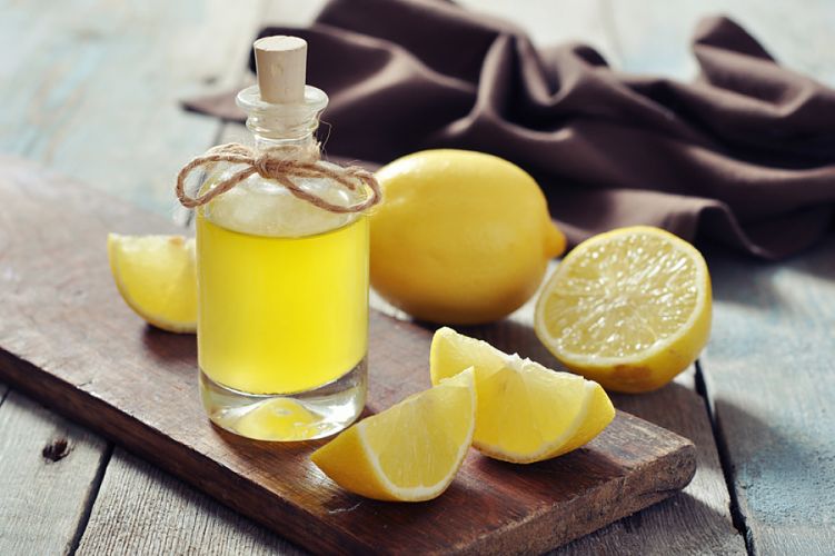 Flacon rempli d'une préparation à base de citron posée sur une table à côté de citrons coupés