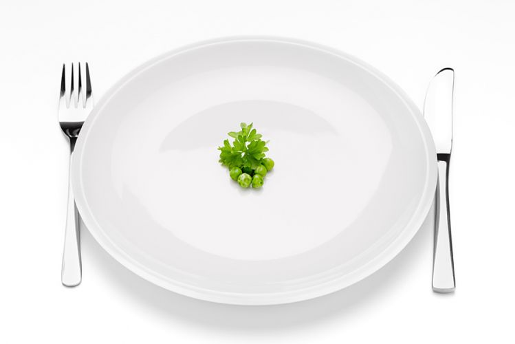 Assiette blanche quasiment vide contenant quelques petits poids et une feuille de persil en son centre