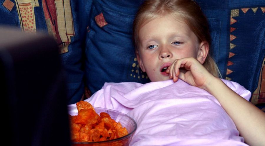 jeune fille mangeant un saladier de chips devant la télévision