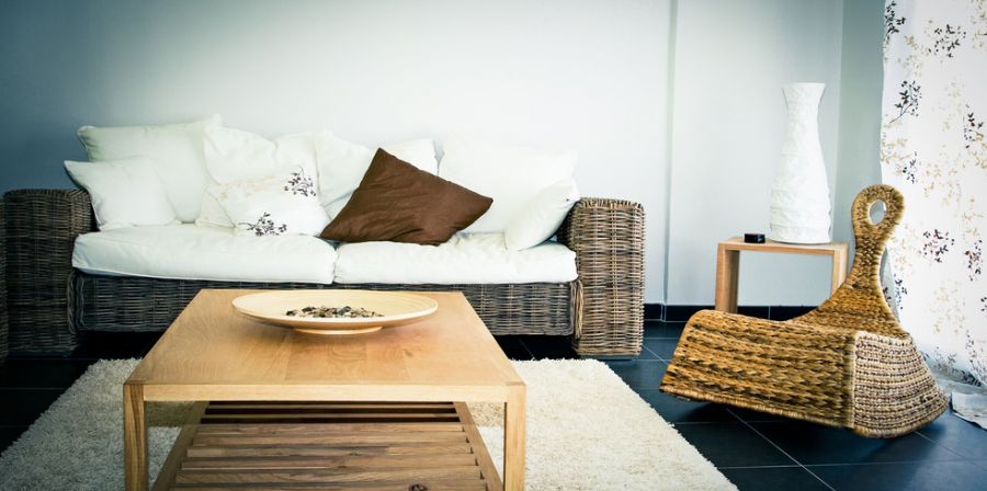 Intérieur d'un salon avec canapé, tapis table basse et fauteuil en rotin
