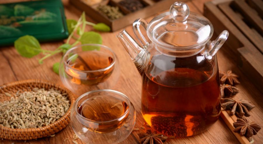 une théière et des tasses de tisane sur une table en bois avec des épices