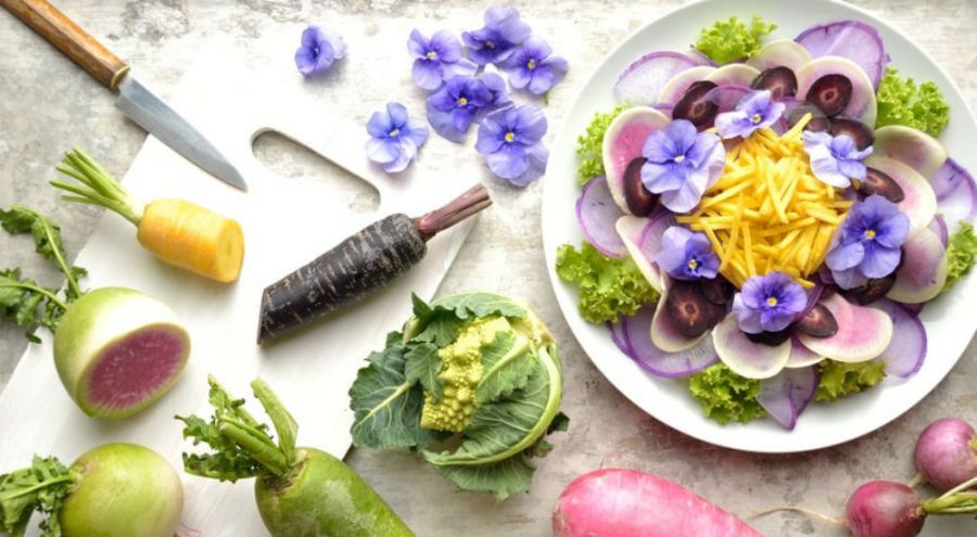 une salade de fleurs et de légumes sur une table