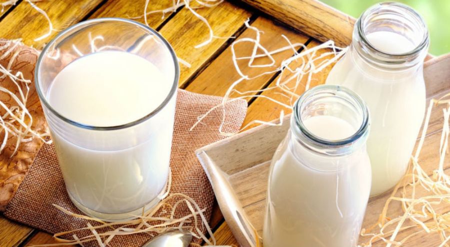 du lait de vache en bouteille et dans un verre sur une table en bois