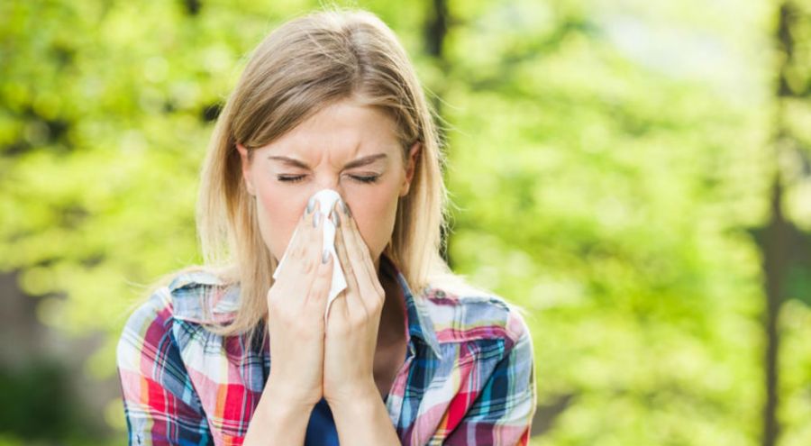 une femme allergique au pollen se mouche