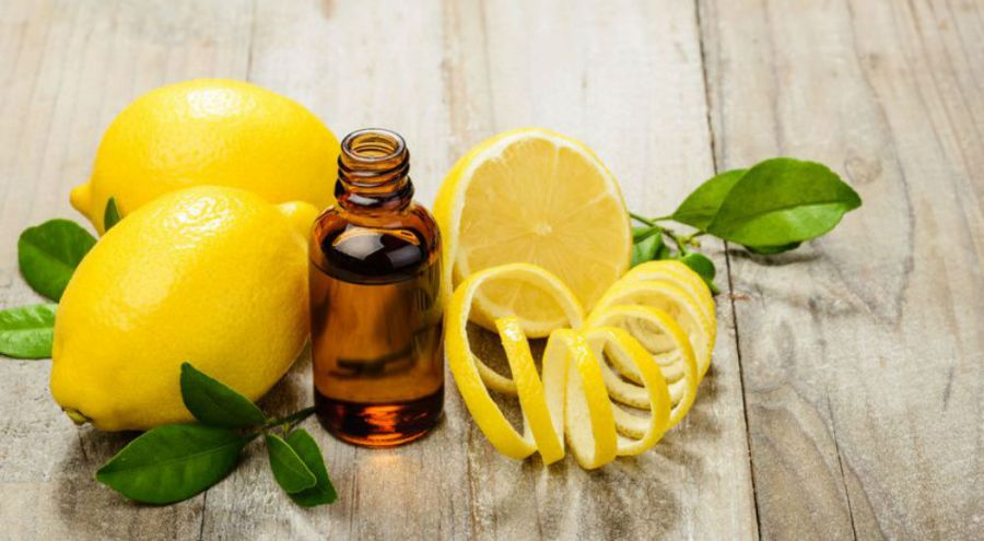 des citrons jaunes et de l'huile essentielle de citron dans une petite bouteille en verre brun