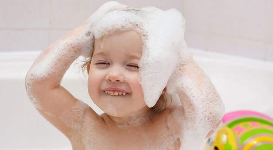 un enfant se fait un shampoing dans une baignoire