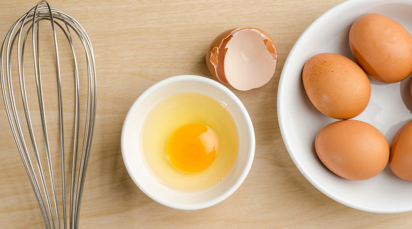 un œuf dans un bol à côté d'un fouet en cuisine